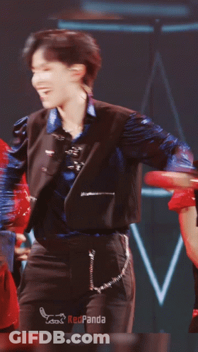 Man In Blue Jacket And Black Pants Dancing In Front Of Redpanda Sign GIF