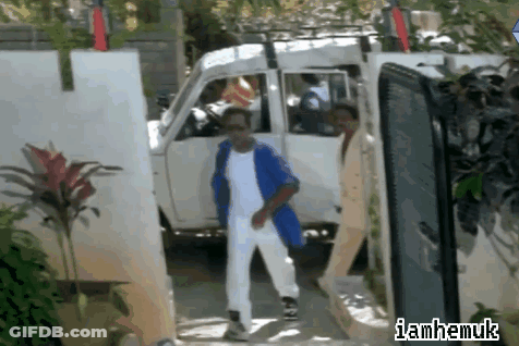 Man In Blue Jacket And White Pants Walking Past Van With Iamhamuk Sign GIF