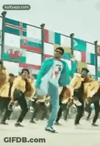 Man In Blue Jacket Dancing By Fence With Flags GIF