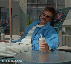 Man In Blue Jacket Holding Drink And Smoking GIF