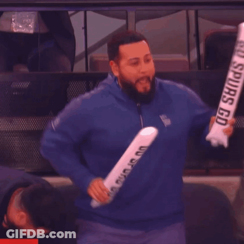 Man In Blue Jacket Holding Spurs Sign GIF