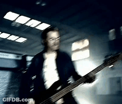 Man In Blue Jacket Playing Bass Guitar In Dark Room GIF