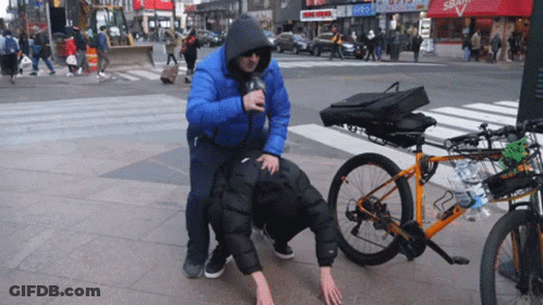 Man In Blue Jacket Pushes Leashed Man Next To Bike GIF