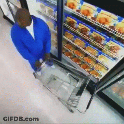 Man In Blue Jacket Pushing Shopping Cart In Front Of Refrigerator GIF