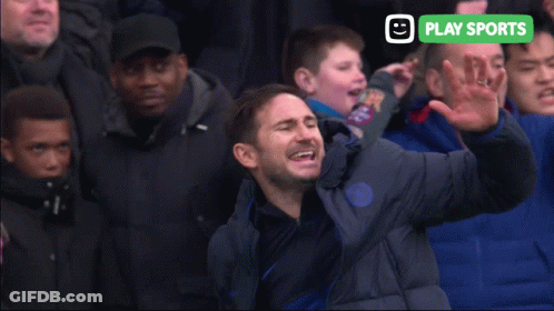 Man In Blue Jacket Screaming In Front Of Crowd With Play Sports Sign GIF