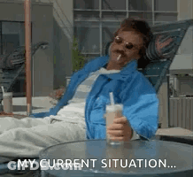 Man In Blue Jacket Sitting Holding Drink And Cigarette GIF