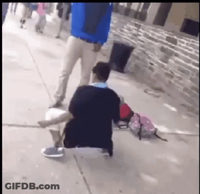 Man In Blue Jacket Standing Beside Kneeling Man GIF