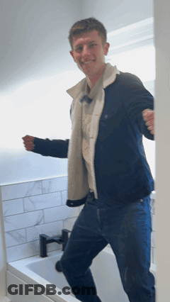 Man In Blue Jacket Standing In Front Of Bathtub GIF