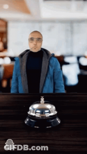 Man In Blue Jacket Standing Next To Bell GIF
