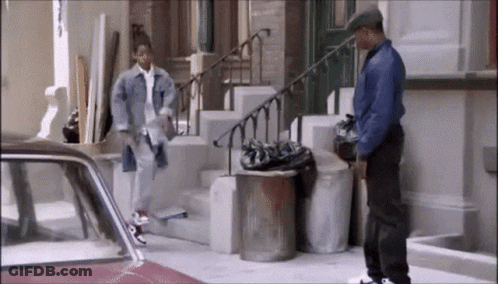 Man In Blue Jacket Standing Next To Trash Can GIF
