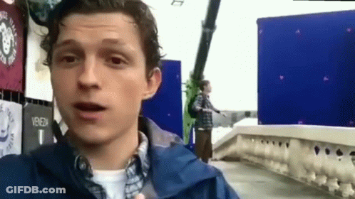 Man In Blue Jacket Standing On Bridge Talking GIF