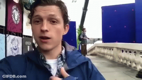 Man In Blue Jacket Standing On Sidewalk In Front Of Blue Wall GIF