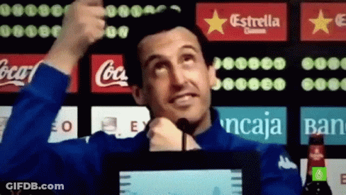 Man In Blue Jacket Thumbs Up In Front Of Coca Cola And Estrella Ads GIF