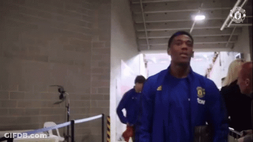 Man In Blue Jacket Walking Hallway GIF