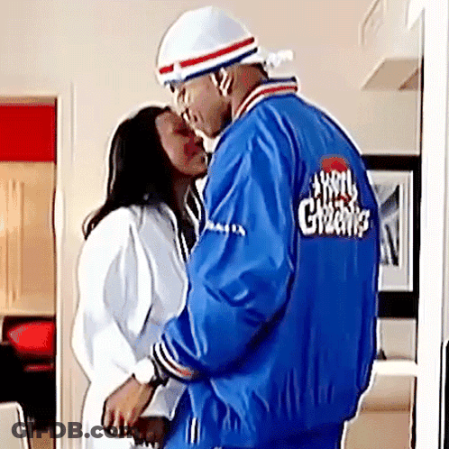 Man In Blue Jacket With Greens Kissing Woman In White Robe GIF