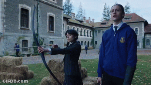Man In Blue Jacket With M Next To Woman With Bow And Arrow GIF