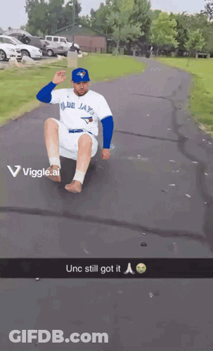Man In Blue Jays Shirt Sliding Down Road GIF