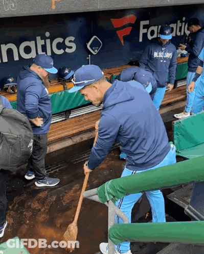 Man In Blue Jays Sweatshirt Sweeping Dirt In Dugout GIF