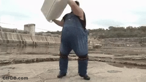 Man In Blue Overalls Holding White Bucket Over Head By Water GIF