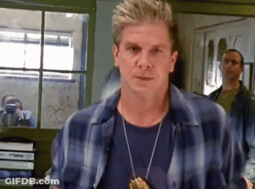 Man In Blue Plaid Shirt And Badge By Window GIF