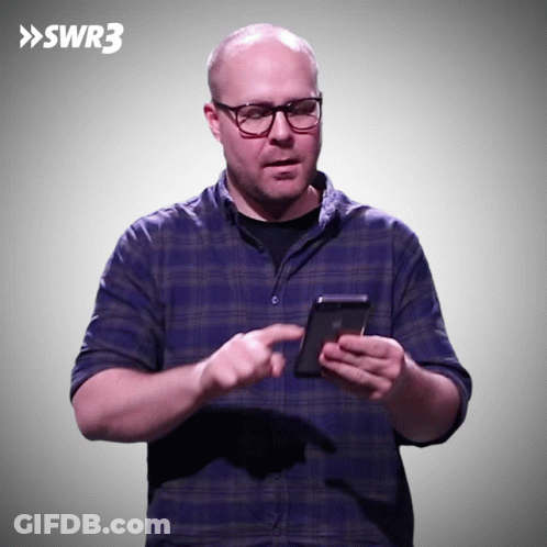 Man In Blue Plaid Shirt Holding Phone In Front Of SWR3 Sign GIF