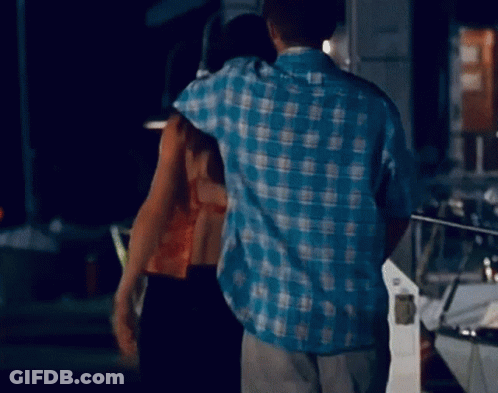 Man In Blue Plaid Shirt Hugging Woman In Dark Room GIF