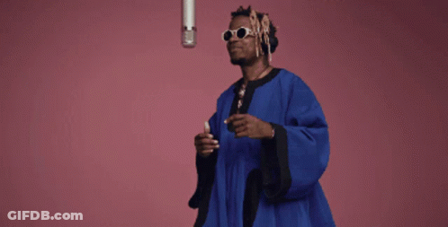 Man In Blue Robe At Microphone On Pink Background GIF