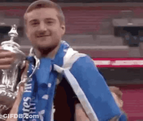 Man In Blue Scarf Holding Trophy GIF