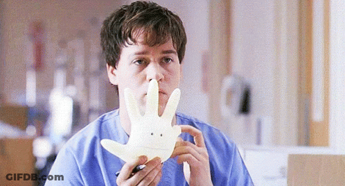 Man In Blue Scrub Holding Smiley Face Glove GIF