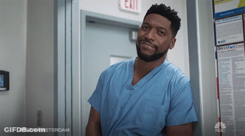 Man In Blue Scrub Leaning Against Exit Sign GIF
