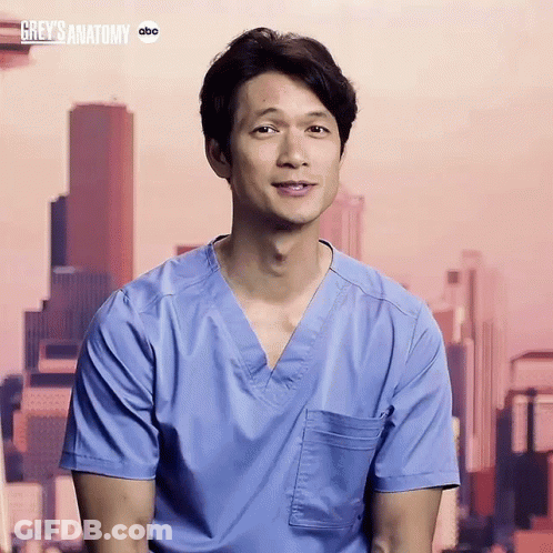 Man In Blue Scrub Smiling In Front Of Grey's Anatomy Sign GIF