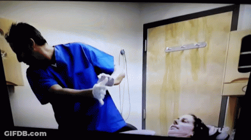 Man In Blue Scrubs Cleaning Patient's Face GIF