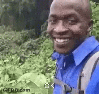 Man In Blue Shirt And Backpack Smiling GIF
