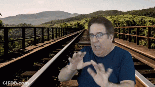 Man In Blue Shirt And Glasses On Train Tracks GIF