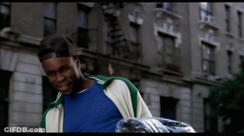 Man In Blue Shirt And Green Jacket Carrying Trash Bag GIF