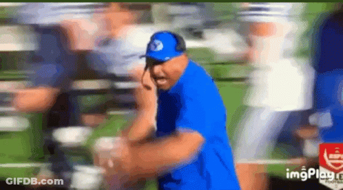 Man In Blue Shirt And Hat Talking On Cell Phone In Field GIF