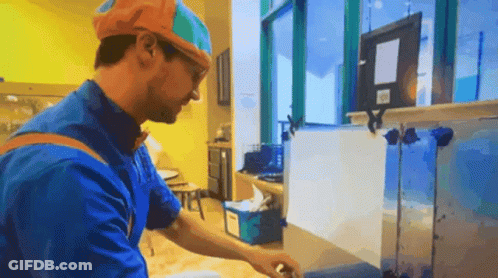 Man In Blue Shirt And Orange Hat Working In Kitchen GIF