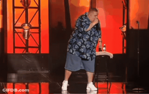 Man In Blue Shirt And Shorts Holding Microphone On Stage GIF