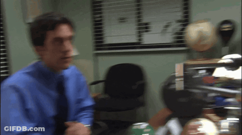 Man In Blue Shirt And Tie Standing By Window GIF