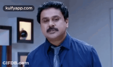 Man In Blue Shirt And Tie Standing In Room GIF