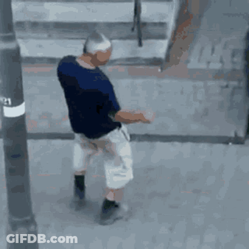 Man In Blue Shirt And White Shorts Walking On Street GIF