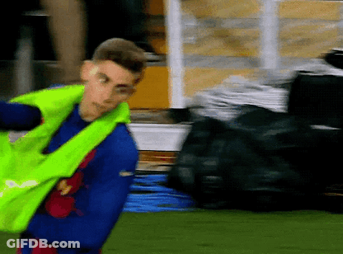 Man In Blue Shirt And Yellow Vest Standing On Field GIF