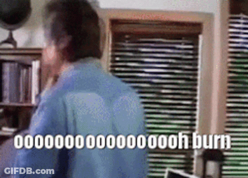 Man In Blue Shirt By Window With Blinds And Burn Sign GIF