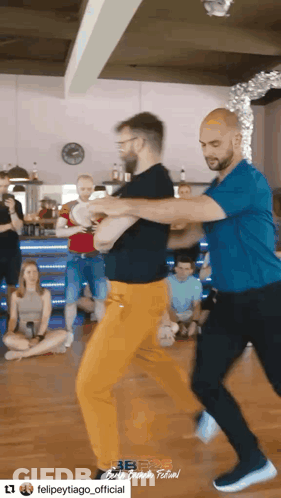 Man In Blue Shirt Dancing With Man In Orange Pants GIF