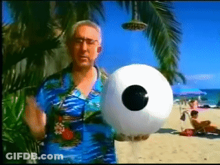 Man In Blue Shirt Holding Inflatable Ball With Eye GIF