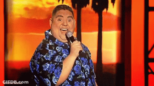 Man In Blue Shirt Holding Microphone Smiling On Stage GIF
