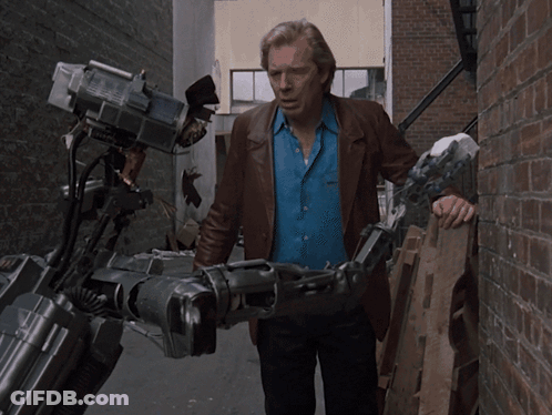 Man In Blue Shirt Holding Robotic Arm GIF