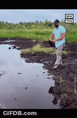 Man In Blue Shirt Holding Shovel In Muddy Field GIF