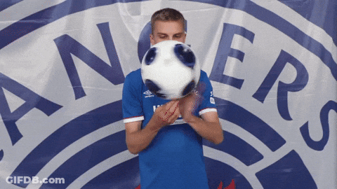 Man In Blue Shirt Holding Soccer Ball In Front Of Rangers Logo GIF