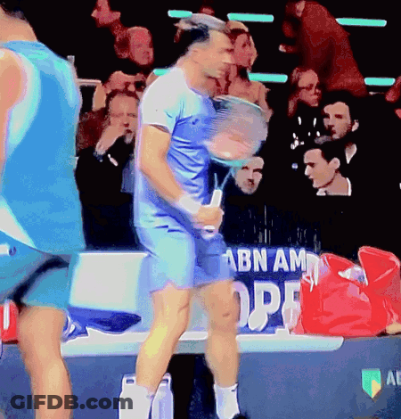 Man In Blue Shirt Holding Tennis Racquet In Front Of ABN AM OPE Banner GIF